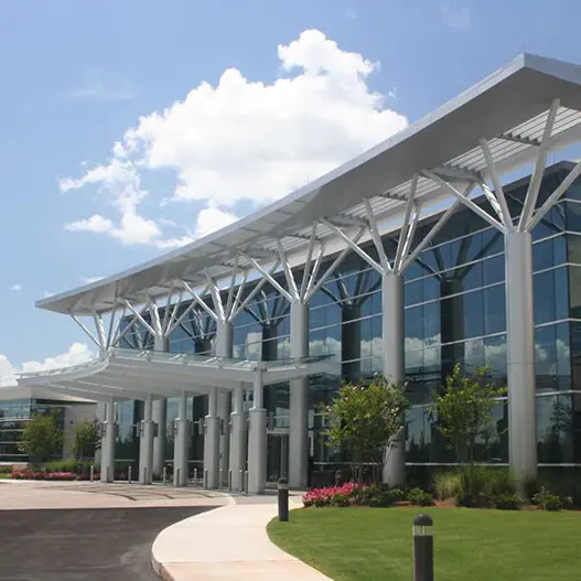 Modern hospital entrance with glass facade and architectural canopy.